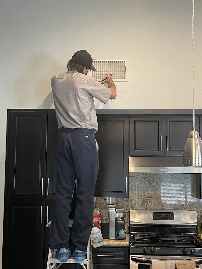 Technician inspecting an air vent during HVAC service in Johnson City